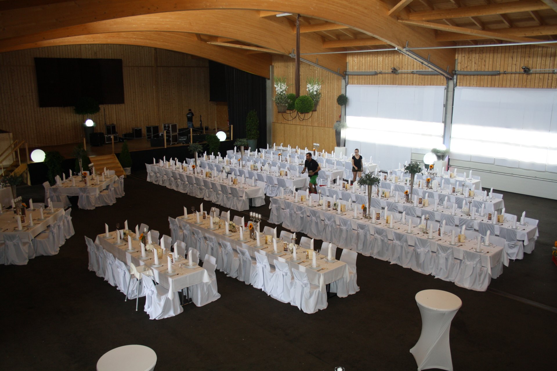 Großer Saal mit mehreren langen Tischreihen und Bühne